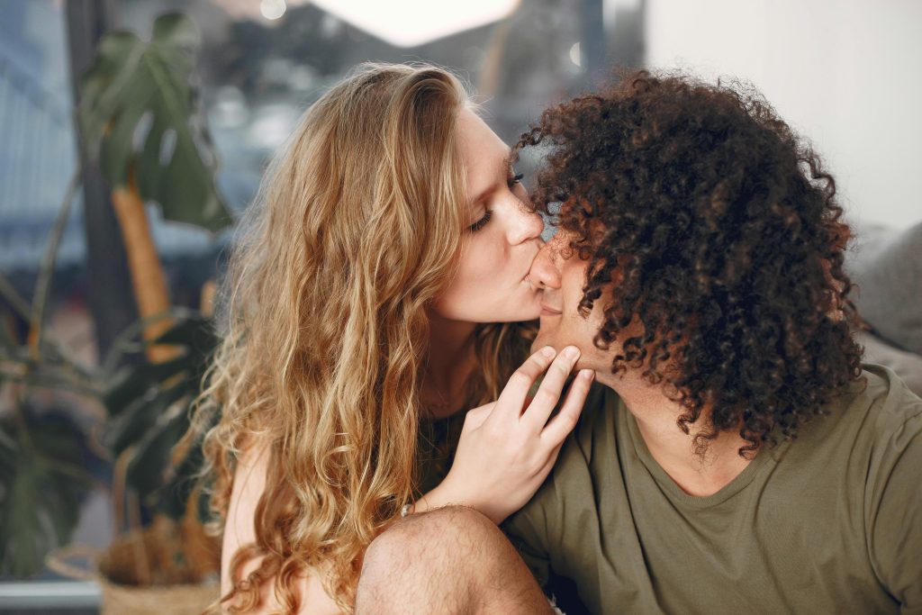 A loving couple shares a tender kiss in a cozy indoor setting, capturing romance.